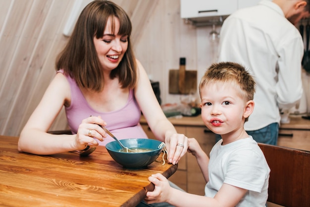 Moeder met vader die het kind in de keuken voedt met pasta