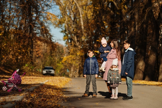 Moeder met vier kinderen in herfstpark. Familie wandeling in herfst bos.