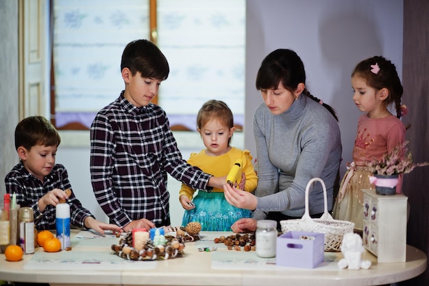 Moeder met vier kinderen maakt een krans voor kerstavond en knutselt het decoreren. Nieuwjaarsviering.