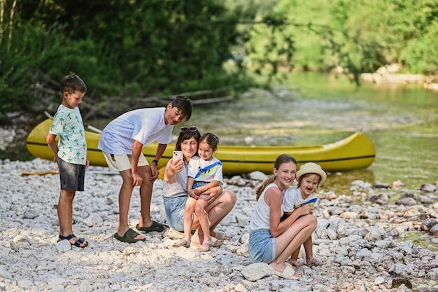 Moeder met vijf kinderen tegen kano in rotsachtige kust van een kalme rivier in Triglav Nationaal Park Slovenië