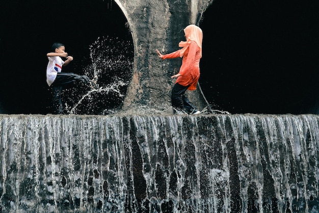 Foto moeder met zoon genieten van een waterval op een rotsformatie