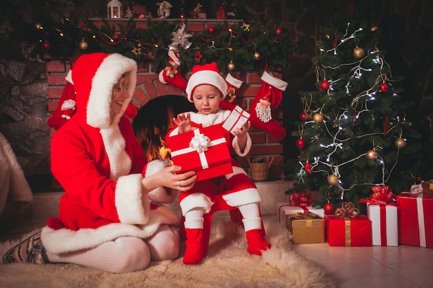 Moeder met zoon zitten bij de open haard en openen geschenken - Kerstversiering