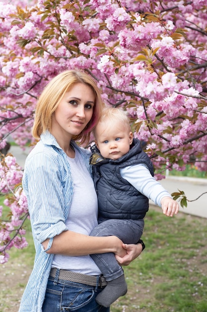 Moeder met zoontje in het park lopen in de buurt van de sakura-boom