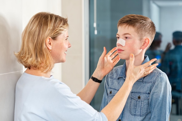 Foto moeder plakt een pleister om mee-eters te verwijderen op haar zoon acne remover patch tiener met neusband