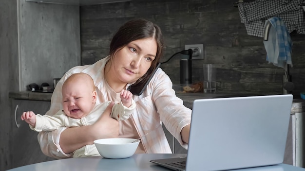 Moeder probeert te werken en eet met huilende baby op schoot