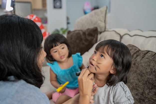 Moeder schildert haar kinderen in het gezicht