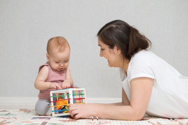 Moeder speelt speelgoed met opgewonden babymeisje en geniet van het weekend