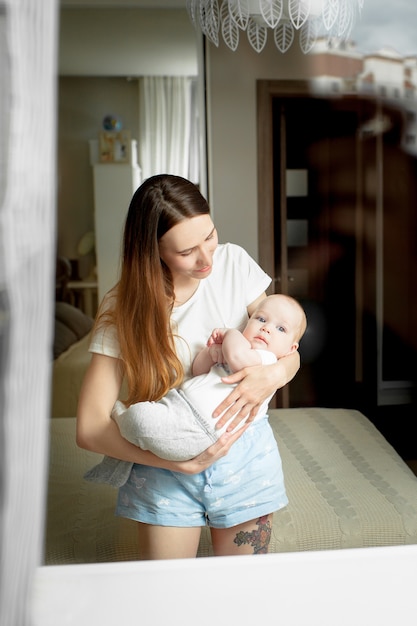 Moeder speelt thuis met de baby 6 maanden op het bed