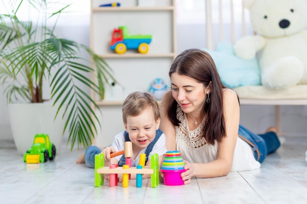 Moeder speelt thuis met het kind in het educatieve speelgoed in de kinderkamer Een gelukkig liefdevol gezin