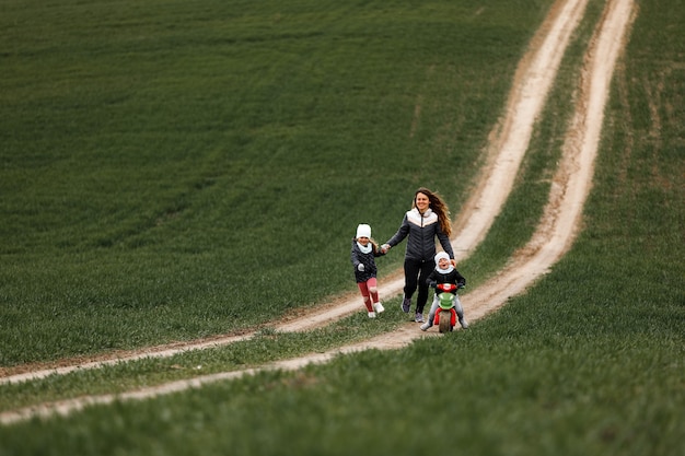 Moeder speelt vrolijk met haar kinderen in het veld. familie concept.