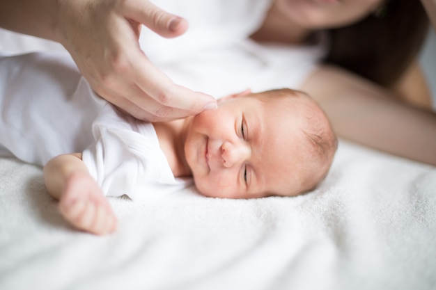 moeder streelt een pasgeboren baby die op het bed ligt