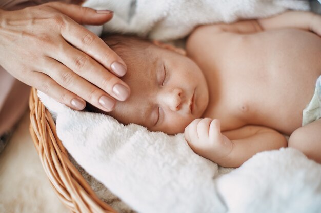 Foto moeder streelt zachtjes haar slapende pasgeboren baby