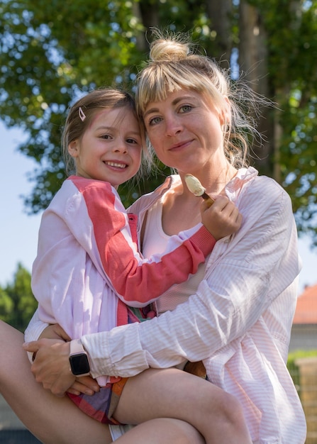 moeder teder haar dochtertje knuffelen Gelukkig lachend meisje met ijs in haar handen