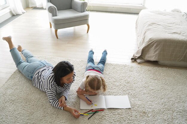 Moeder tekenen met dochtertje liggend op de vloer thuis Kunst hobby children39s onderwijs