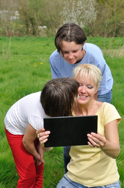 Foto moeder toont dochter digitale tablet terwijl ze op het veld zit