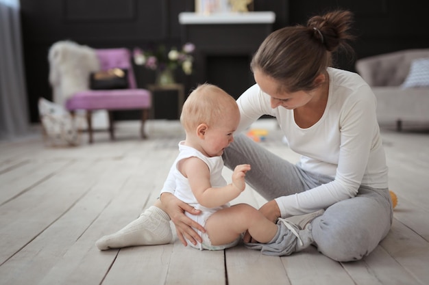 Moeder troost een huilende baby op de vloer in een heldere kamer Het concept van adoptie van moederschap 10