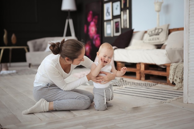 Moeder troost een huilende baby op de vloer in een heldere kamer het concept van moederschap adoptie