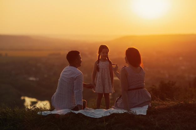 Moeder vader en schattig klein gelukkig meisje kind op de natuur bij zonsondergang