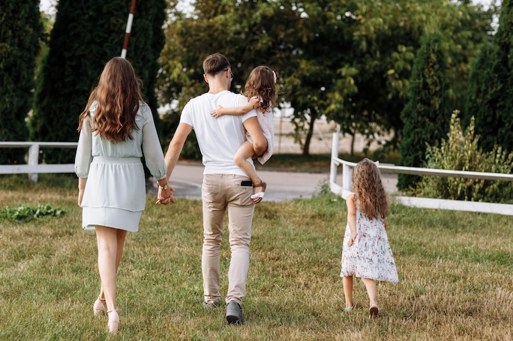 Foto moeder, vader knuffelen dochters genieten van buiten wandelen en kijken naar de natuur. jong gezin tijd samen doorbrengen op vakantie, buitenshuis.