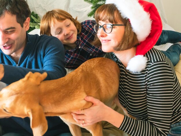 Moeder vader zoon in kerstmutsen en hond op Kerstmis