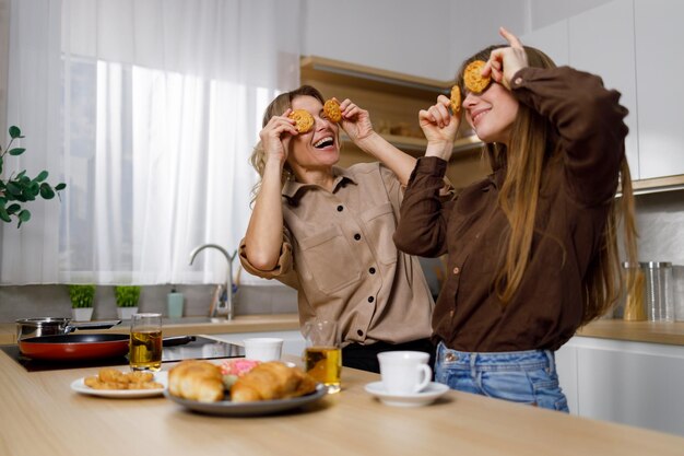 Moeder van middelbare leeftijd en haar tienerdochter spelen met koekjes