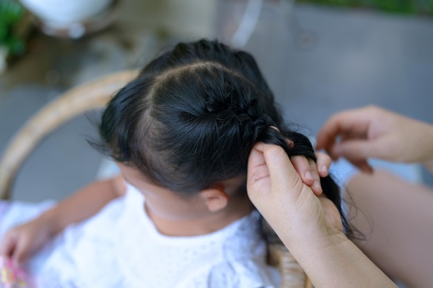 Moeder vlecht het haar van haar dochter buiten