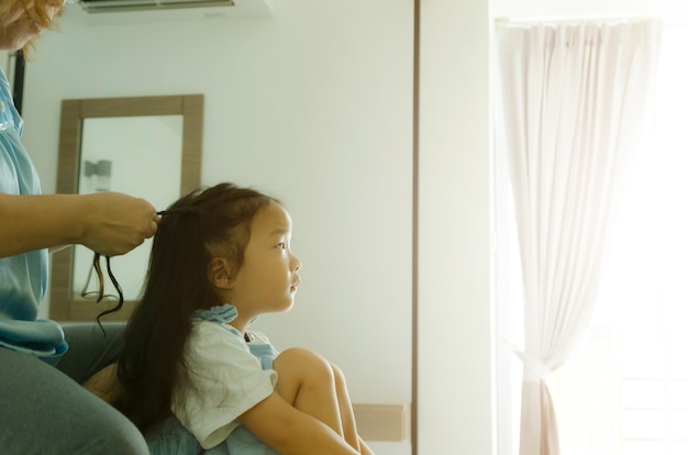 moeder vlecht het haar voor kinderen met zonsopgang van raam, warme toon