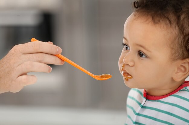 Moeder voedende baby met lepel binnenshuis