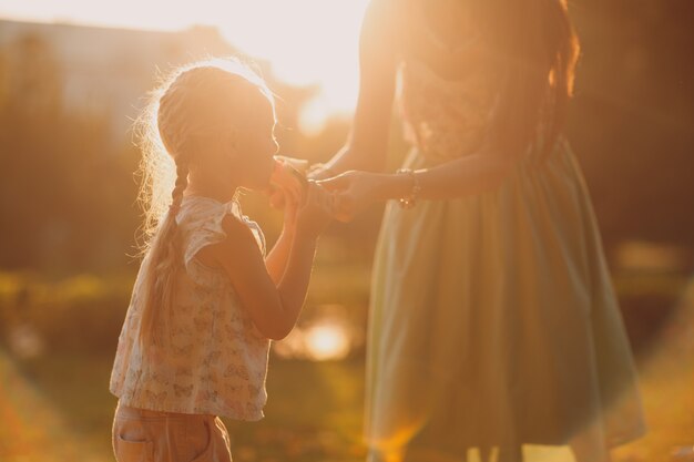 Moeder voedt babymeisje met watermeloen in het park met lensflare. zomer, park, buitenshuis, gezinsleven.