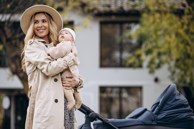 Moeder wandelen met haar pasgeboren kind en kinderwagen in park