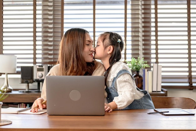 Moeder werkt en geeft les aan dochter voor online leren thuis. Familie saamhorigheid levensstijl en nieuw normaal na Covid-19.