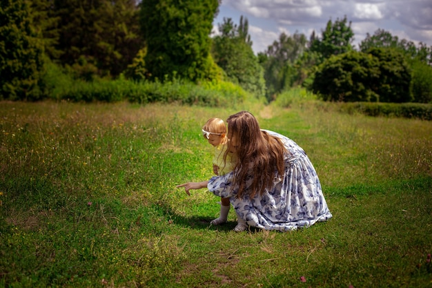 Moeder wijst met haar dochtertje naar het groene gras in de tuin op een warme zomerdag