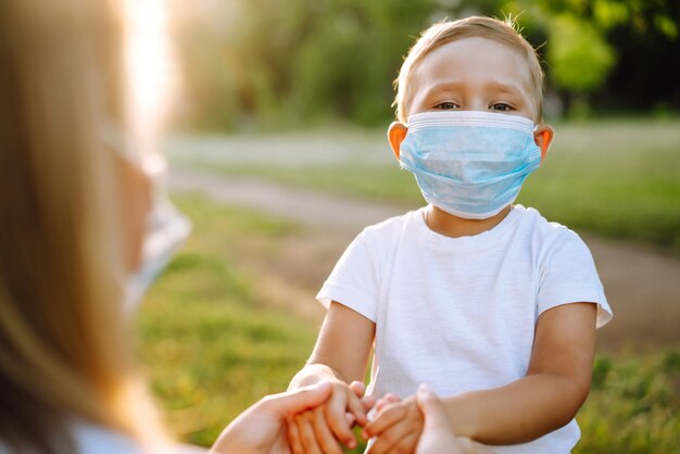 Moeder zet het steriele medische masker van het kind op in het park Covid2019