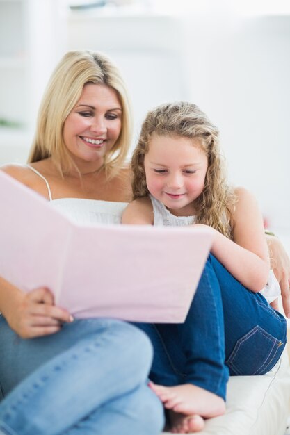 Moeder zit op de bank met haar dochter tijdens het lezen van boek