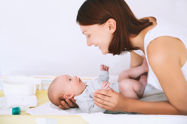 Moeder zorgt voor baby op commode Moeder en glimlachend schattigste pasgeboren kind Babyverzorgingsroutine