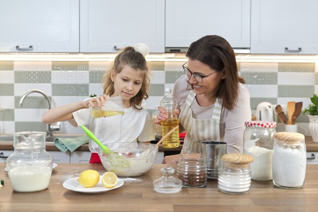 Moederdag, moeder en dochter kind samen thuis keuken koekjes voorbereiden