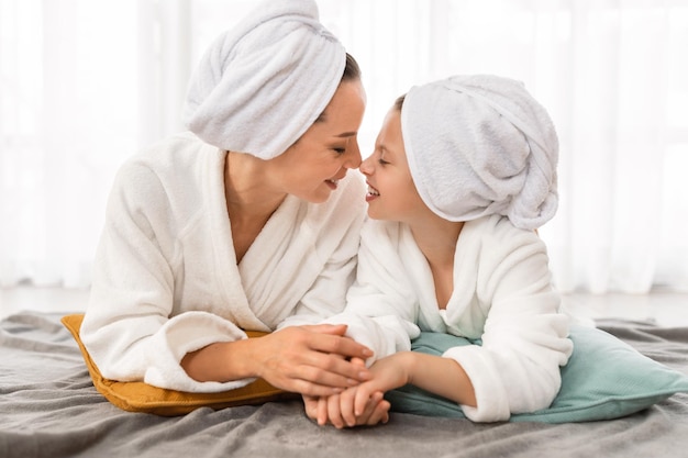 Moederdag moeder en dochtertje dragen badjassen ontspannen samen op bed