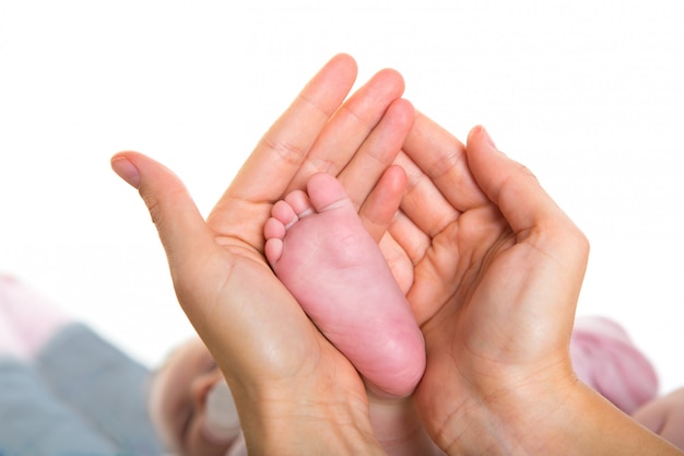 Moederhanden die baby naakte voeten op wit houden