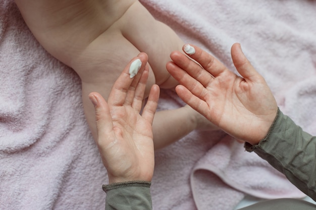 Foto moederhanden die crème op baby aanbrengen na het baden in de kamer handen van een moeder die de voeten van haar baby thuis in bed masseert