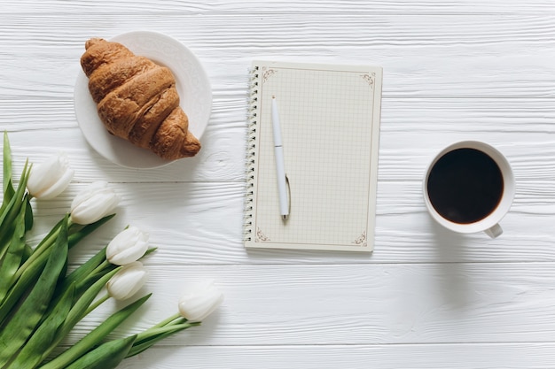 Moeders dag concept. Boeket van tulpen, briefkaart, koffie en een croissant.