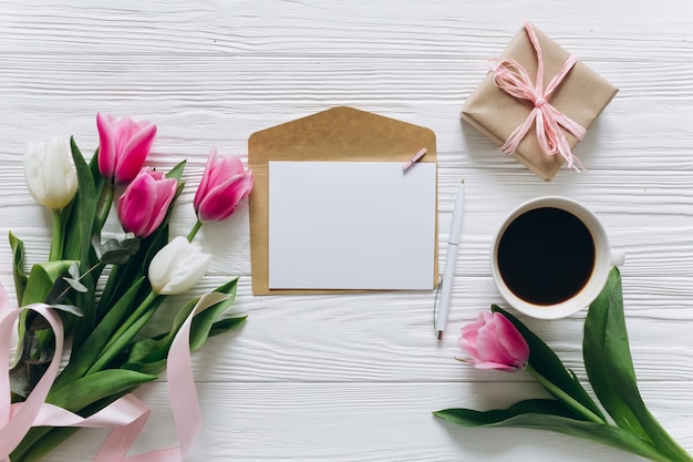 Moeders dag concept. boeket van tulpen, koffie, papier met kopie ruimte en cadeau.