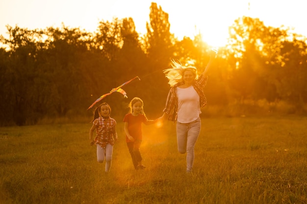 moeders en dochters in een veld bij zonsondergang met een vlieger