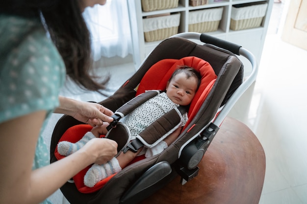 Moeders voorbereiding zet het meisje in een babyzitje