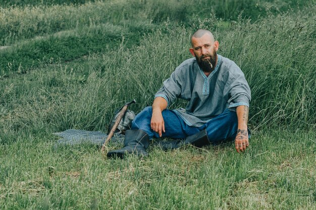 Moedige man met baard rustend in het gras in het veld Peinzende blik