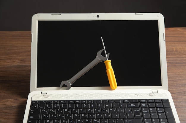 Foto moersleutel en schroevendraaier met een laptop computer it-serviceondersteuning