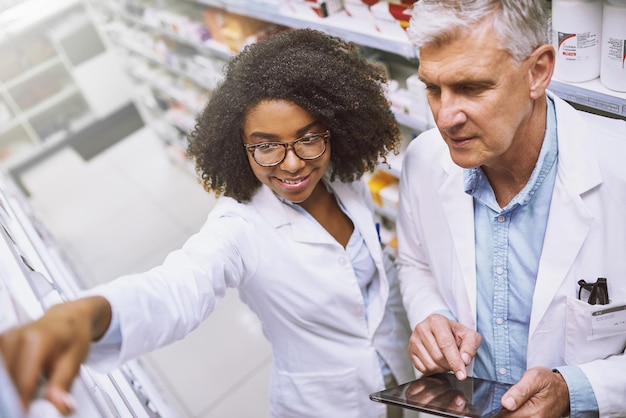 Moeten we meer van deze opname met een hoge hoek krijgen van twee gefocuste apothekers die rondlopen en voorraad doen in een apotheek?