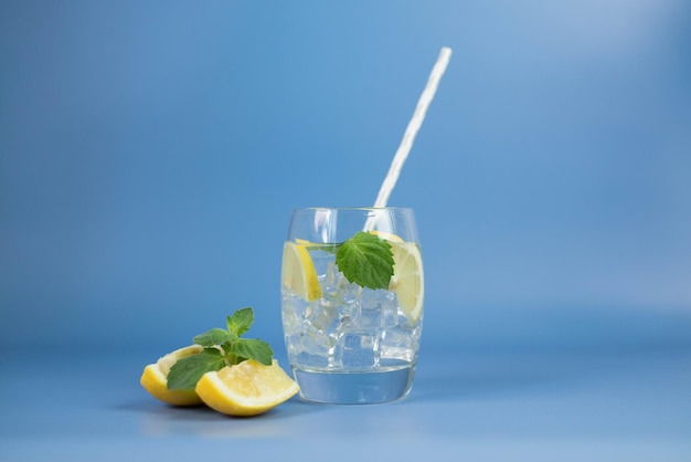 mohito with lemon and leaves of mint on blue background