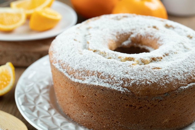 Moist orange fruit cake on plate with orange slices on wooden table Delicious breakfast traditional English tea time Orange cake recipe