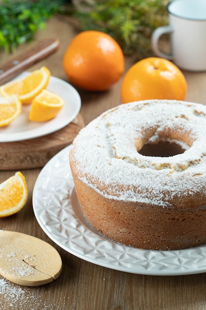 Moist orange fruit cake on plate with orange slices on wooden table Delicious breakfast traditional English tea time Orange cake recipe