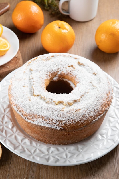 Moist orange fruit cake on plate with orange slices on wooden table Delicious breakfast traditional English tea time Orange cake recipe